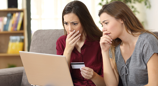 image of worried young women looking at credit card and laptop